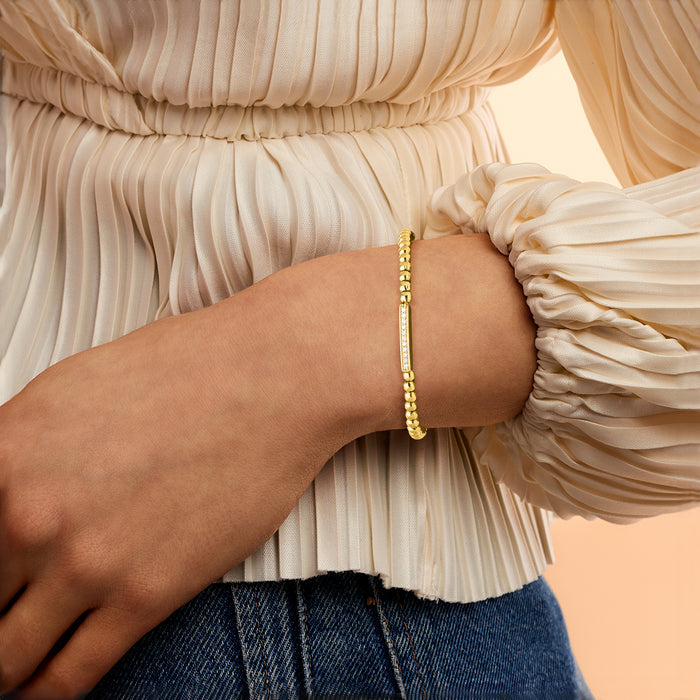 Gold bead stretch bracelet on wrist with rectangular diamond bar