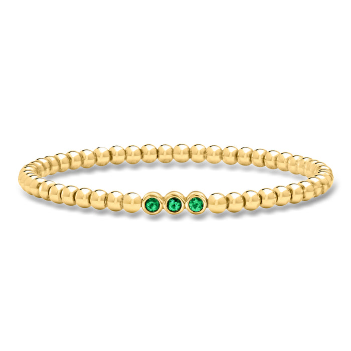 Gold bead stretch bracelet with three green emerald-style stones
