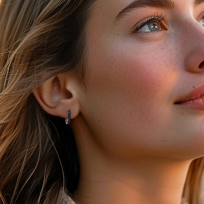 Sterling silver hoop earrings with blue sapphire stones, worn on ear