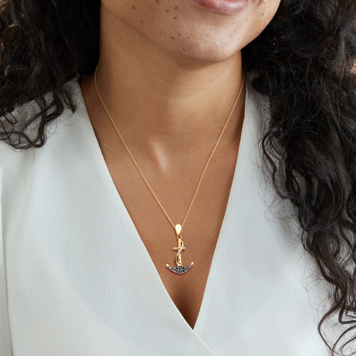 Gold-tone anchor pendant necklace with blue sapphire stones, worn on a fine chain